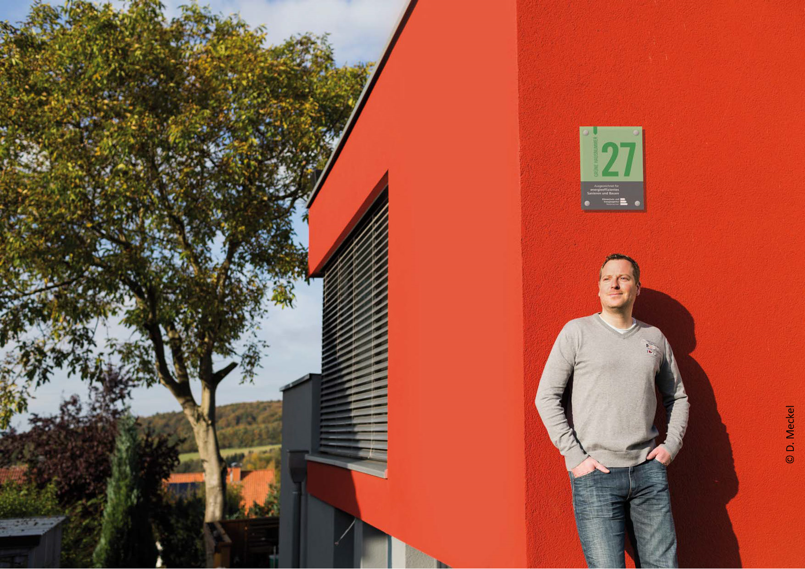 Person vor Haus mit Grüner Hausnummer