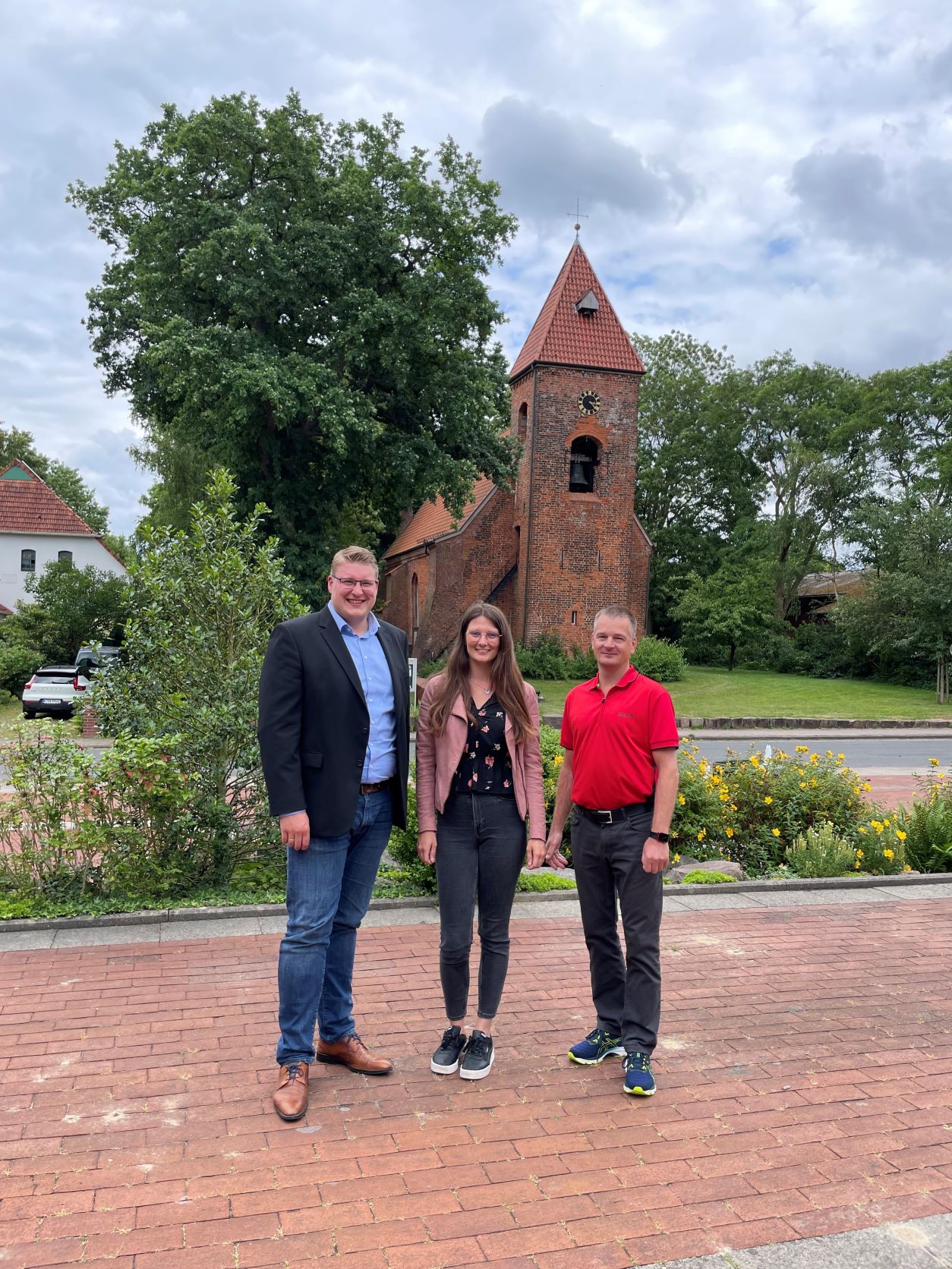 Mitarbeiter der Gemeinde stehen vor dem Rathaus. Im Hintergrund die Kirche. 