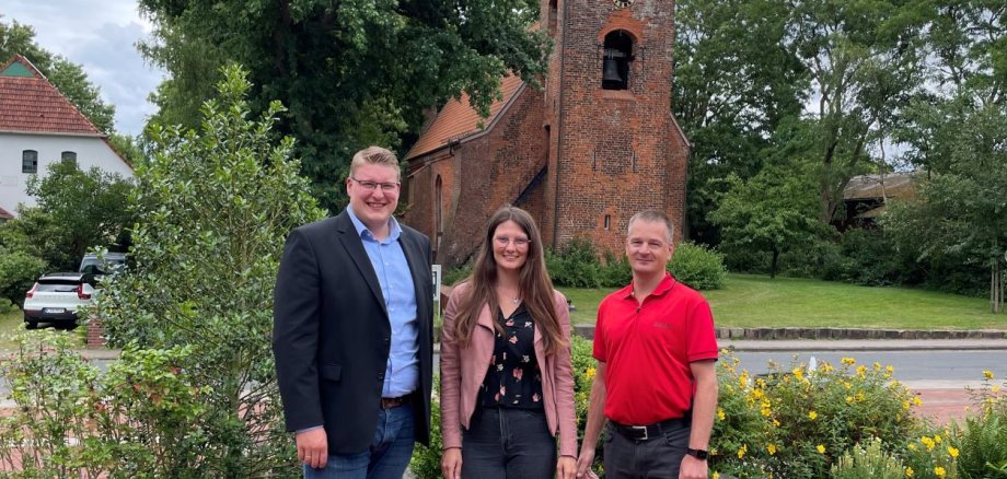 Mitarbeiter der Gemeinde stehen vor dem Rathaus. Im Hintergrund die Kirche. 