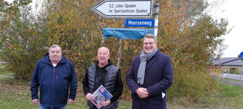 Ortsbürgermeister Fredo Tiedemann, Vereinsvorsitzender Frank Kuthning und Bürgermeister Henrik Wärner vor dem neuen Straßenschild